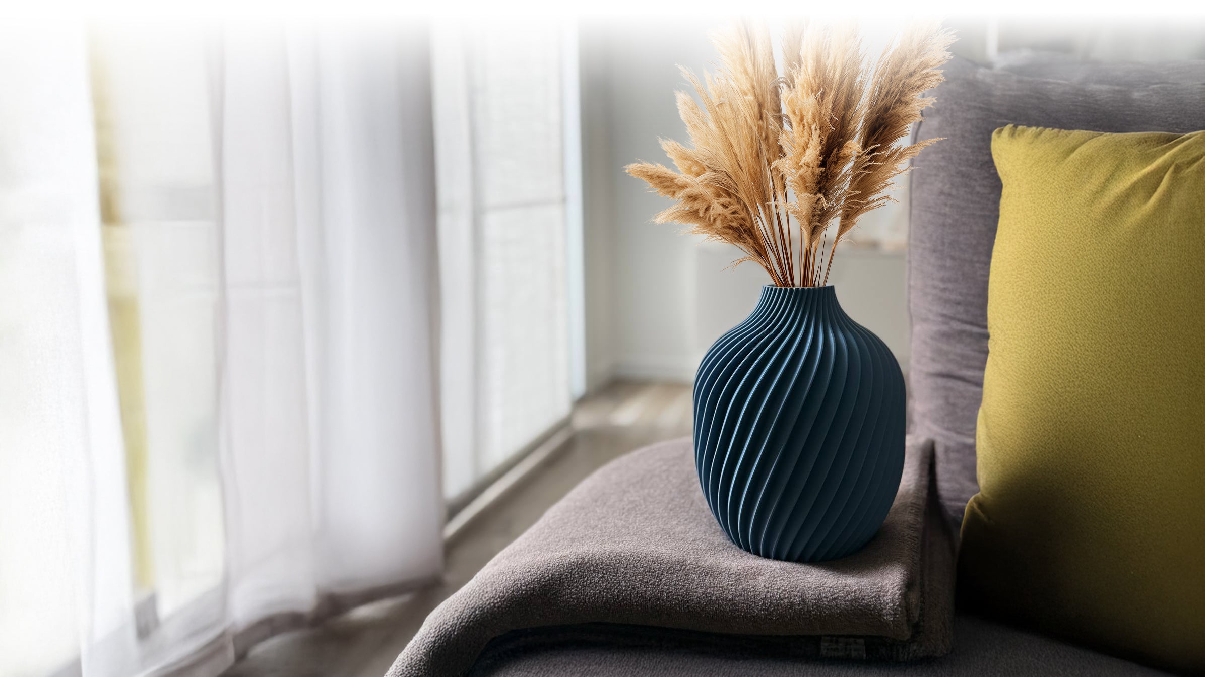 Banner del sito con il vaso di design blu Kivan sopra ad un divano moderno